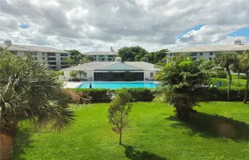 Outdoor swimming pool surrounded by landscaped lawn, mature palms, and structured shrubbery