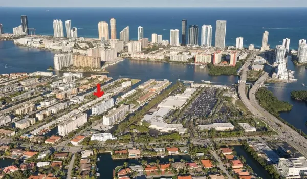 Aerial perspective featuring a multi-story residential building located on a waterfront canal with direct water access