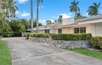 Single-story residence featuring a concrete driveway, stone-veneer exterior accents, tile roof, and terraced landscaping with stone retaining walls