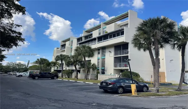 Multi-story residential building exterior featuring concrete facade, screened balconies, and decorative lattice screening