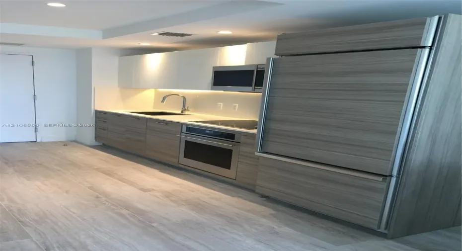 Kitchen featuring flat-panel wood-finish cabinetry, integrated refrigerator, stone countertop, stainless steel oven, and recessed lighting