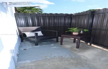 Enclosed patio featuring a concrete floor and a full-height corrugated metal privacy fence