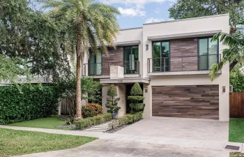 Modern two-story exterior featuring smooth stucco siding, horizontal wood-finish cladding, second-level balconies with metal railings, and an attached multi-car garage
