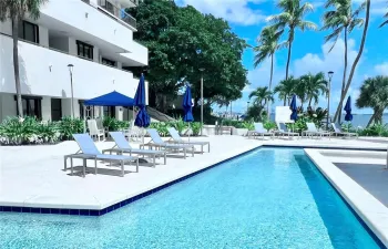 Swimming pool with a stone paver deck, surrounding palm trees, and structural lighting