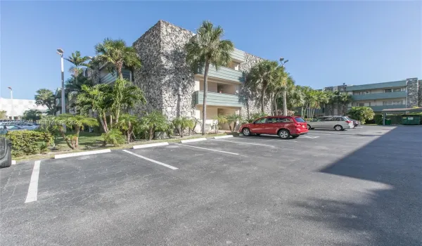 Multi-story building exterior featuring textured stone masonry, private balconies, and landscaped grounds with mature palm trees