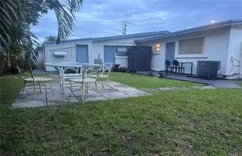 Rear exterior featuring a concrete paver patio, established lawn, and multiple entry points