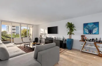 Living area featuring neutral stone flooring, floor-to-ceiling glass sliding doors, and access to a balcony with metal railings