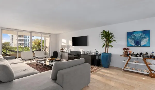 Living area featuring neutral stone flooring, floor-to-ceiling glass sliding doors, and access to a balcony with metal railings
