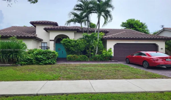 Stucco exterior featuring a multi-gabled clay tile roof, arched entryway, and attached multi-car garage