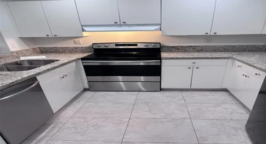 Kitchen featuring white shaker-style cabinetry, stone-finish countertops, stainless steel appliances, a dual-basin stainless steel sink, and ceramic tile flooring