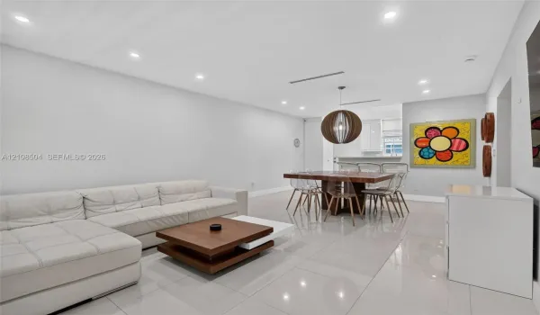 Open-concept interior featuring large-format tile flooring, recessed lighting, and a spherical wood-slat pendant fixture