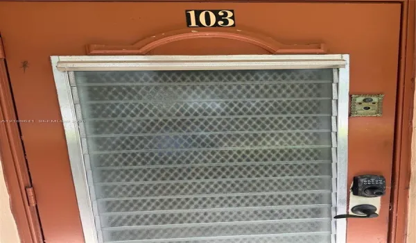 Solid entry door with a decorative arched transom, integrated metal security screen, push-button electronic keypad lock, and antique-style metal doorbell fixture