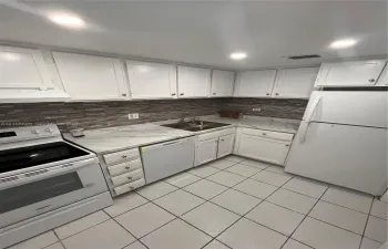 Kitchen featuring white cabinetry, stone-patterned countertops, a decorative tile backsplash, recessed lighting, and tile flooring