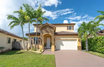 Two-story residence featuring a tile roof, stone-veneer entryway, stucco exterior, attached garage, and paved driveway