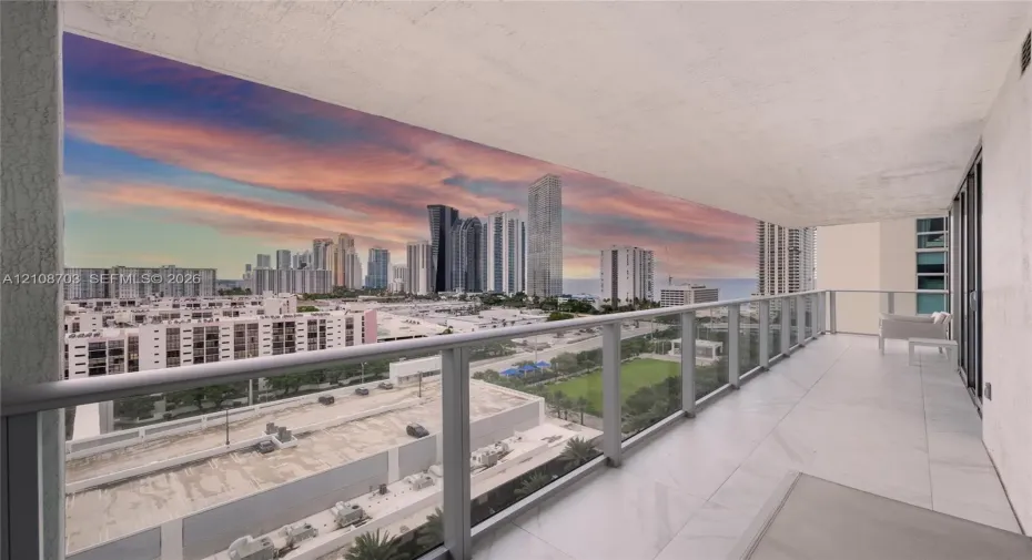 Private balcony featuring light-toned tile flooring and a glass-paneled railing, offering an elevated perspective of the urban skyline