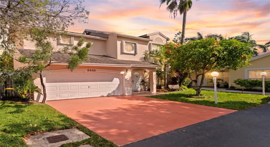 Two-story exterior featuring a stucco facade, an arched entryway, a double-car garage, and a paved driveway
