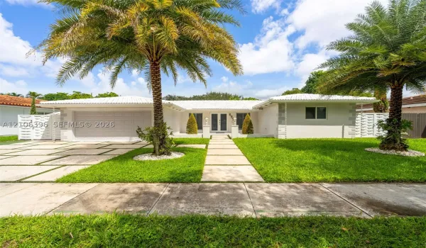 Single-story exterior featuring a light-toned facade, decorative corner quoins, a crisp white tile roof, an integrated garage, and a geometric paver driveway