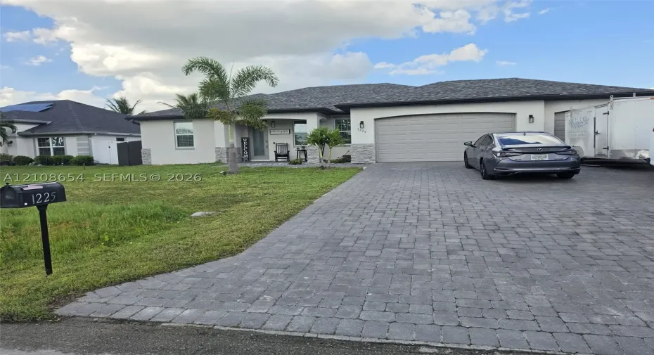 Single-story exterior featuring a stone-veneer facade, paver driveway, covered entryway, and multi-car garage