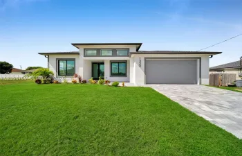 Modern single-story exterior featuring a flat roofline, clerestory windows, concrete paver driveway, two-car garage, and smooth stucco finish