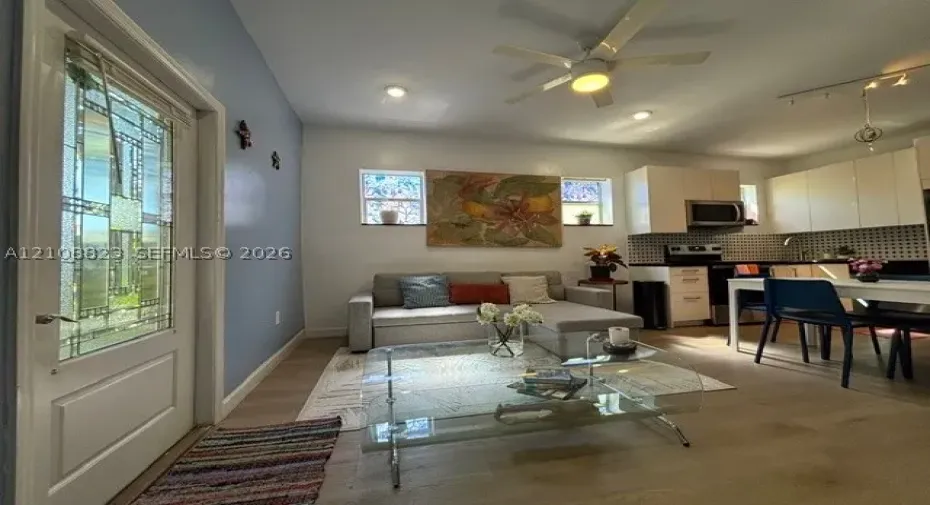 Entry door with decorative glass inlay, wood-finish flooring, recessed lighting, ceiling fan, and white cabinetry