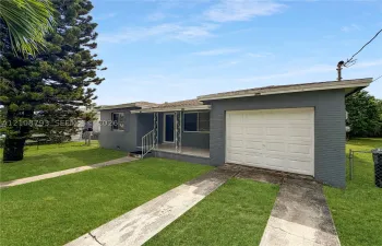 Single-story exterior featuring painted masonry siding, a covered front porch with decorative metal railing, and an attached one-car garage
