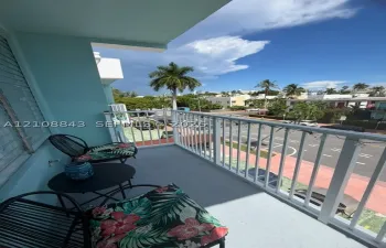 Covered exterior balcony featuring a white metal railing and solid-surface flooring