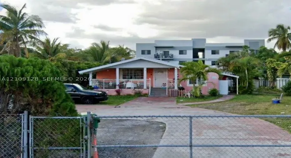 Single-story residence featuring a covered front porch, concrete driveway, and chain-link perimeter fencing