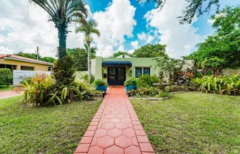 Light green exterior with a blue fabric awning and dark entry doors