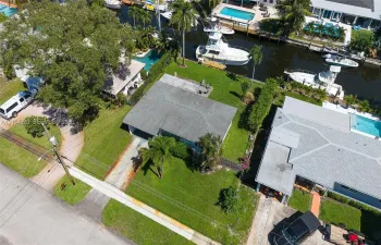 Waterfront property featuring a canal-front bulkhead, private boat slip, paved driveway, and established landscaping
