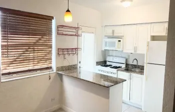 Kitchen featuring a stone-surface breakfast bar, white cabinetry, integrated microwave, and pendant lighting