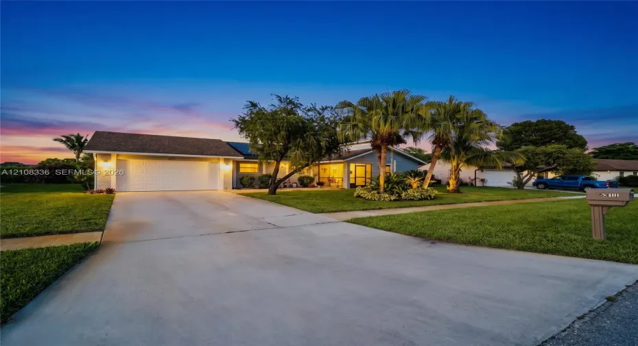 Single-story residence featuring a shingled roof, attached two-car garage, concrete driveway, and mature landscaping