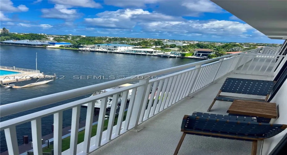 Private balcony featuring a white metal railing and a direct outlook over the waterway and surrounding coastal landscape