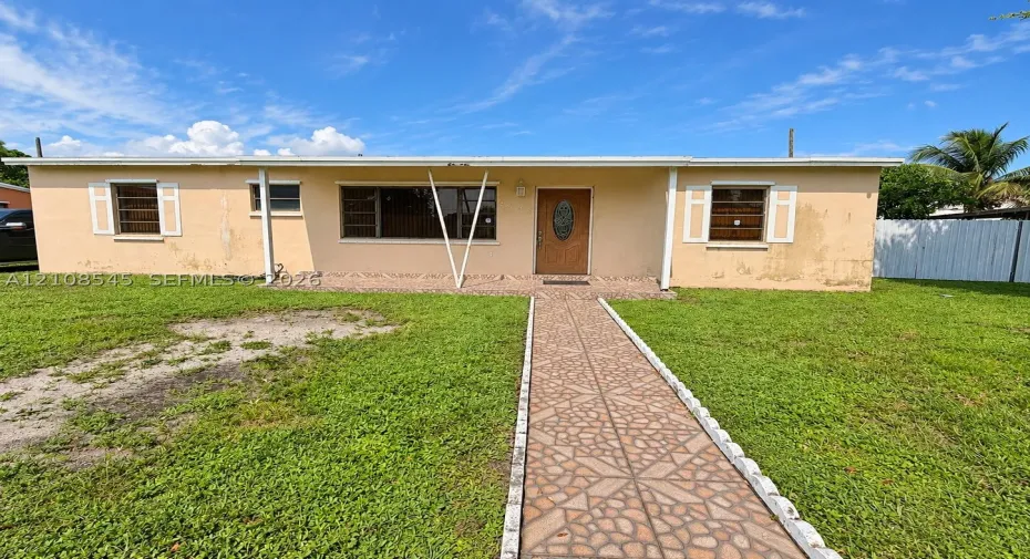 Single-story residence featuring a covered front porch, decorative front entry door, tiled walkway, and louvered window shutters