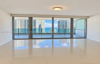 Floor-to-ceiling sliding glass doors, expansive covered balcony, polished tile flooring, and flush-mount lighting