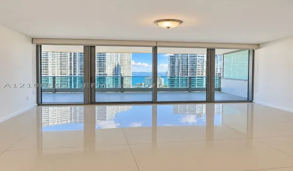 Floor-to-ceiling sliding glass doors, expansive covered balcony, polished tile flooring, and flush-mount lighting