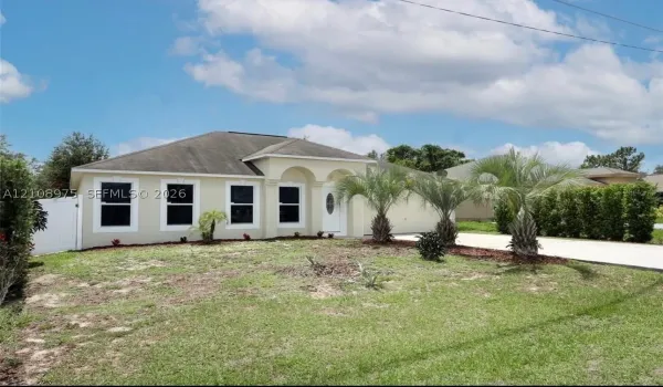 Stucco exterior featuring arched entry detailing, multi-pane windows, and a paved driveway