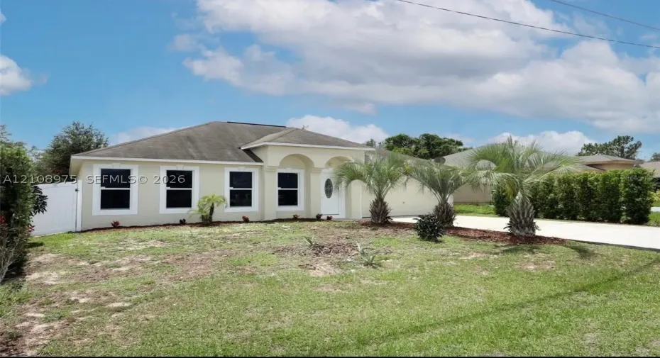Stucco exterior featuring arched entry detailing, multi-pane windows, and a paved driveway