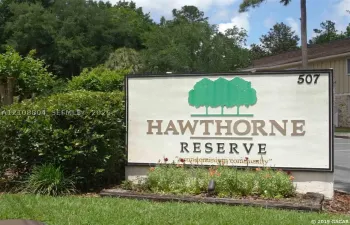Freestanding Hawthorne Reserve monument signage featuring professional lettering, integrated landscape bed, and mature evergreen plantings