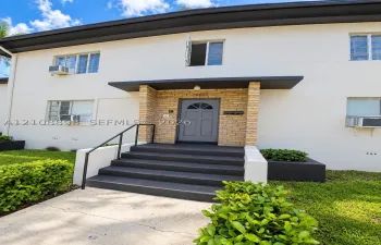 Exterior facade featuring a smooth stucco finish, stone-veneer entryway accents, gray-painted concrete stairs with metal handrails, and built-in landscape planters