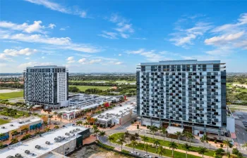 High-rise urban development featuring staggered balcony architectural detailing, expansive multi-story structural design, integrated street-level commercial space, and manicured tropical landscaping