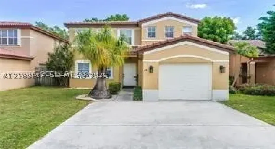 Two-story stucco exterior featuring a tiled roof, arched entryway, and an attached single-car garage with a concrete driveway