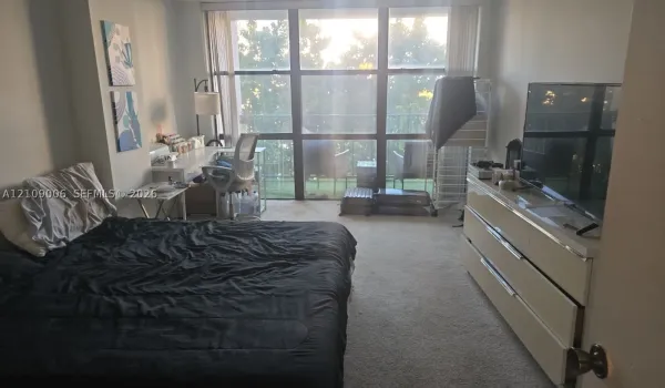 Floor-to-ceiling windows featuring balcony access and neutral carpeting