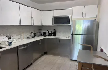 Kitchen featuring white upper cabinetry, stainless steel lower cabinets, light-toned countertop, textured backsplash, and stainless steel appliances