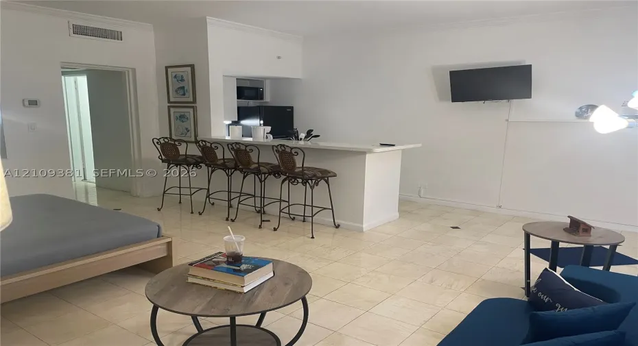 Neutral-tone floor tiles and built-in wet bar featuring a peninsula counter