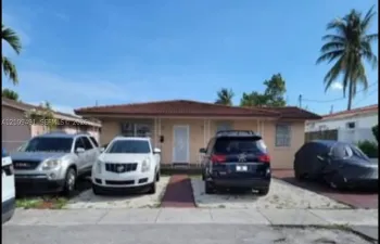 Single-story residence featuring a low-slope roof with barrel-style tiles, concrete exterior, and a multi-car parking area