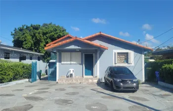 Single-story exterior featuring a clay tile roof, concrete driveway with decorative inlays, and gated side access