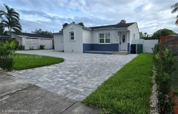 Single-story exterior featuring a two-tone facade, expansive paver driveway, front porch, and manicured lawn