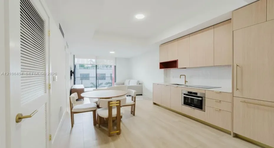 Kitchen featuring light wood-finish cabinetry, quartz countertops, an integrated refrigerator, recessed lighting, and wood-finish flooring