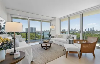 Floor-to-ceiling glass walls, recessed lighting, wood-finish flooring, and a private balcony featuring a metal railing