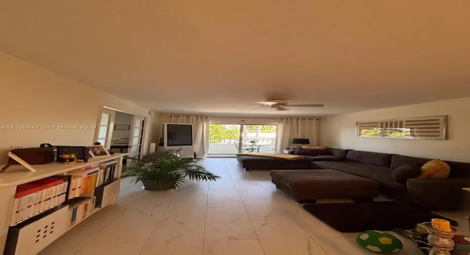 Large-format tile flooring, ceiling fan, and sliding glass doors providing external access